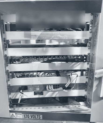 Photograph of an open junction box rack with converters, terminations and a 120 volt label.